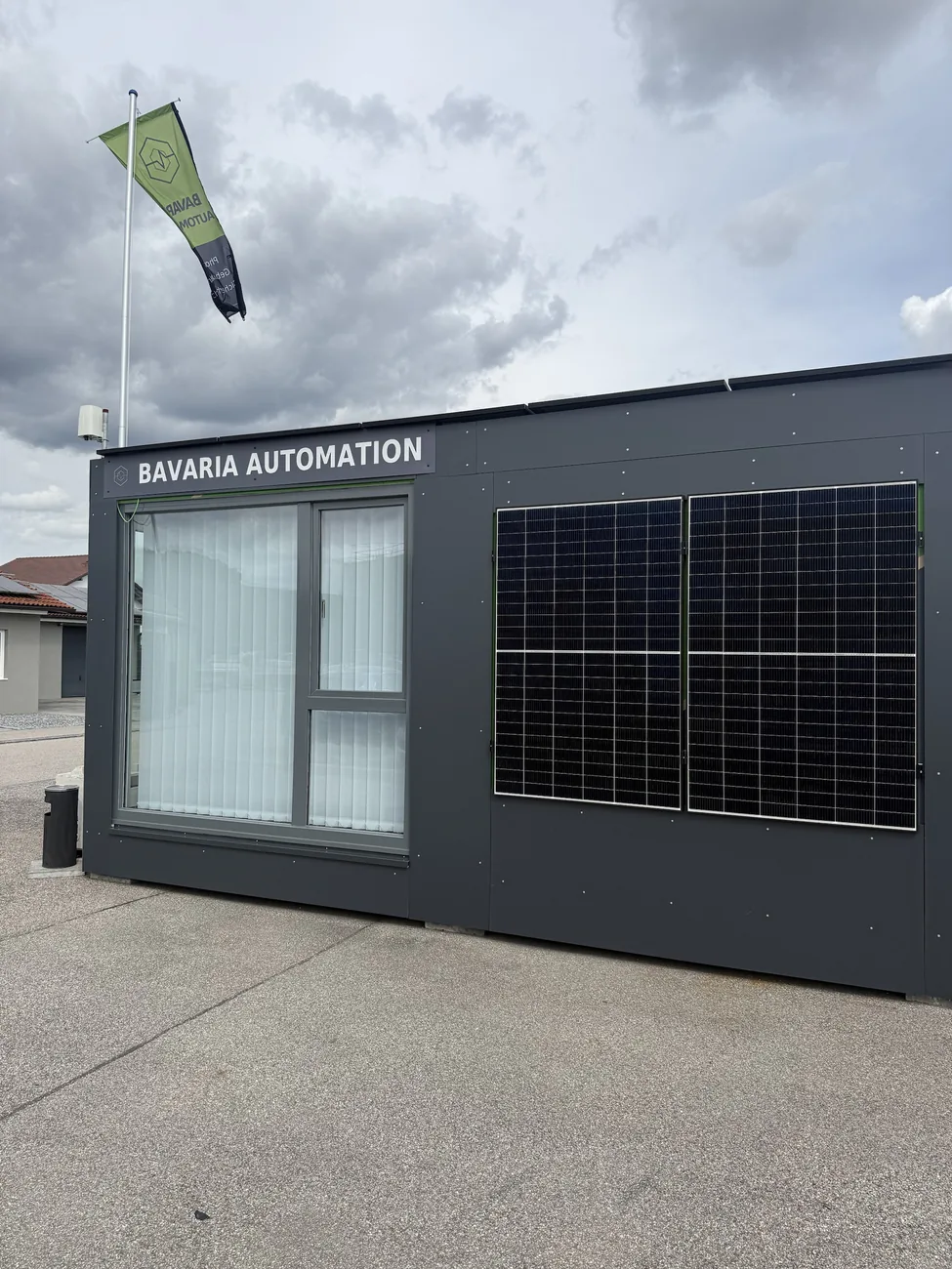 Außenansicht des Showrooms mit Bavaria-Automation-Flagge und Photovoltaik-Modulen an der Fassade