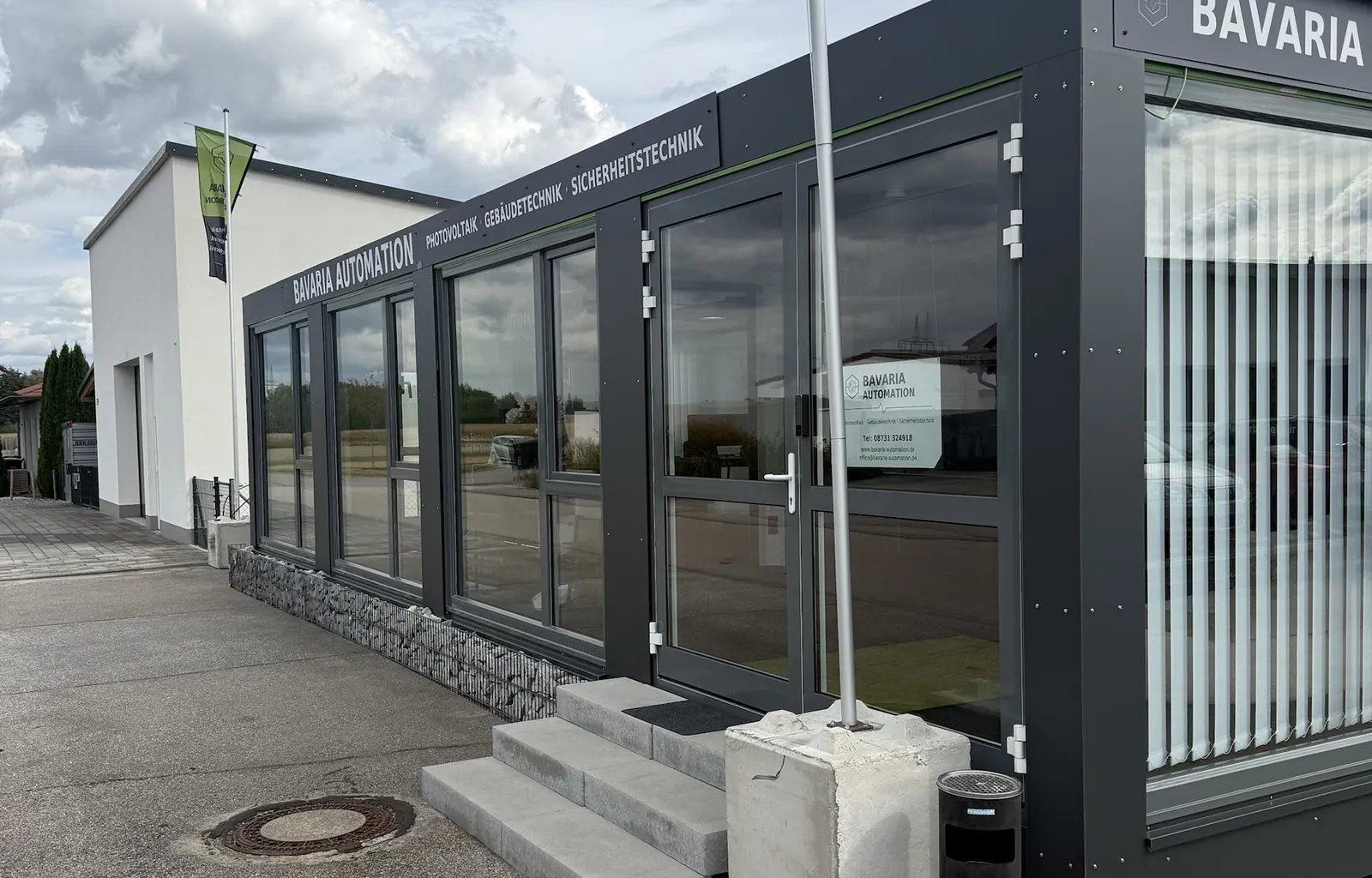 Showroom von Bavaria Automation in Loiching mit Fahne – Photovoltaik, Gebäude- und Sicherheitstechnik zum Anfassen