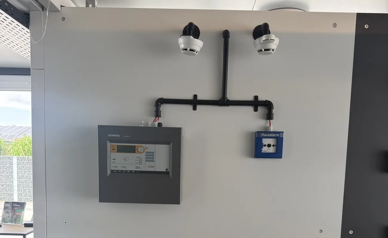 Siemens-Brandmeldezentrale mit Rauchmeldern und Hausalarm-Taster im Showroom